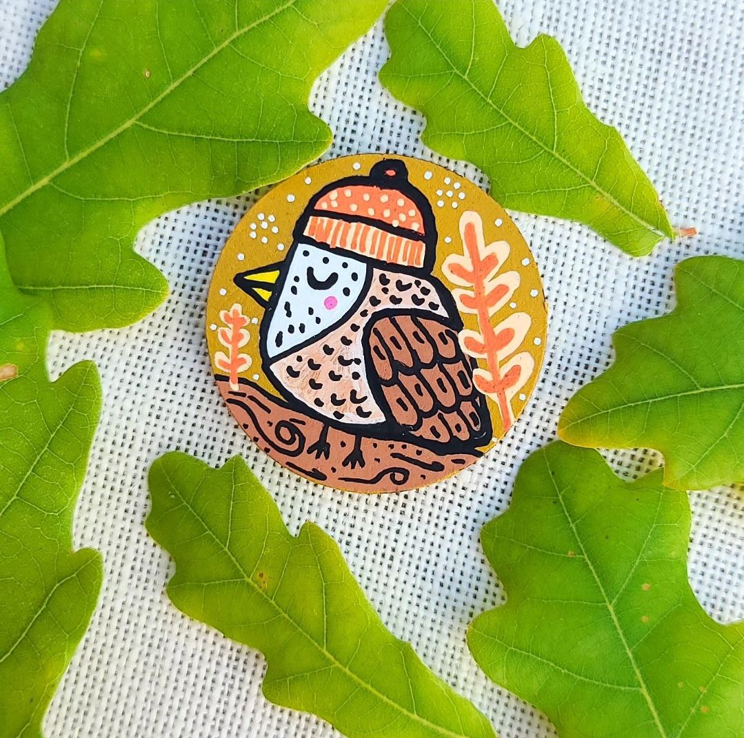 illustration of bird wearing beanie hat on needle minder