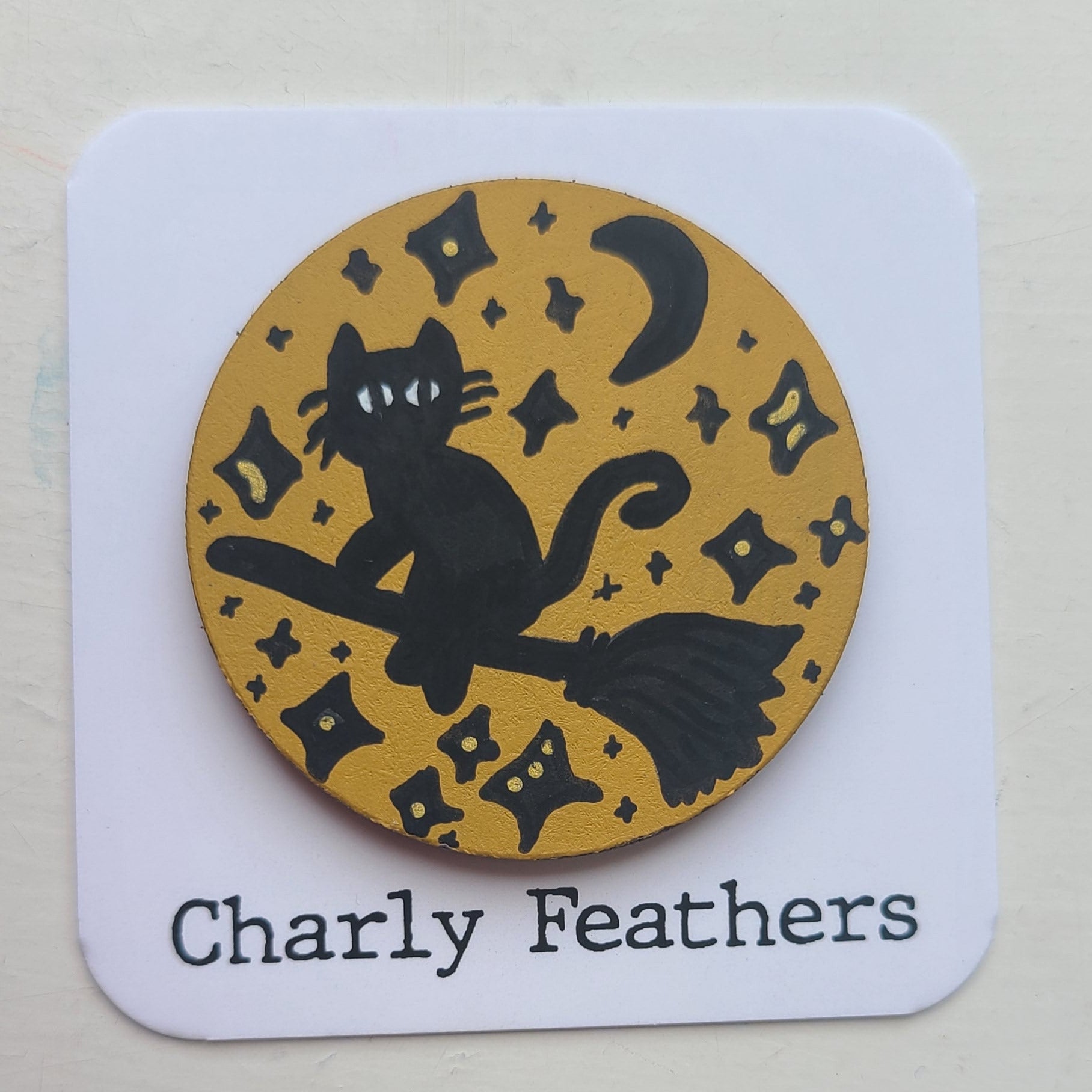 illustration of silhouette of cat on witches broom on yellow ochre needle minder