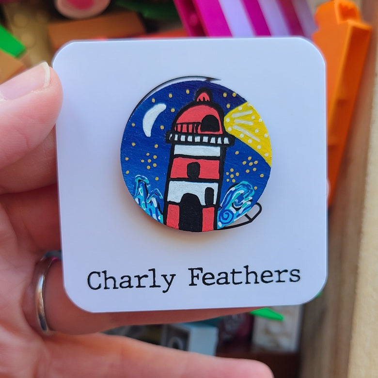 colourful lighthouse illustration on small needle minder with charly feathers branding in the background