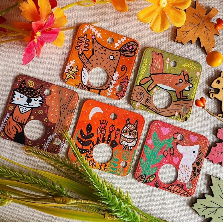 Set of decorative card floss drops with animal illustrations on a textured surface with flowers and leaves.