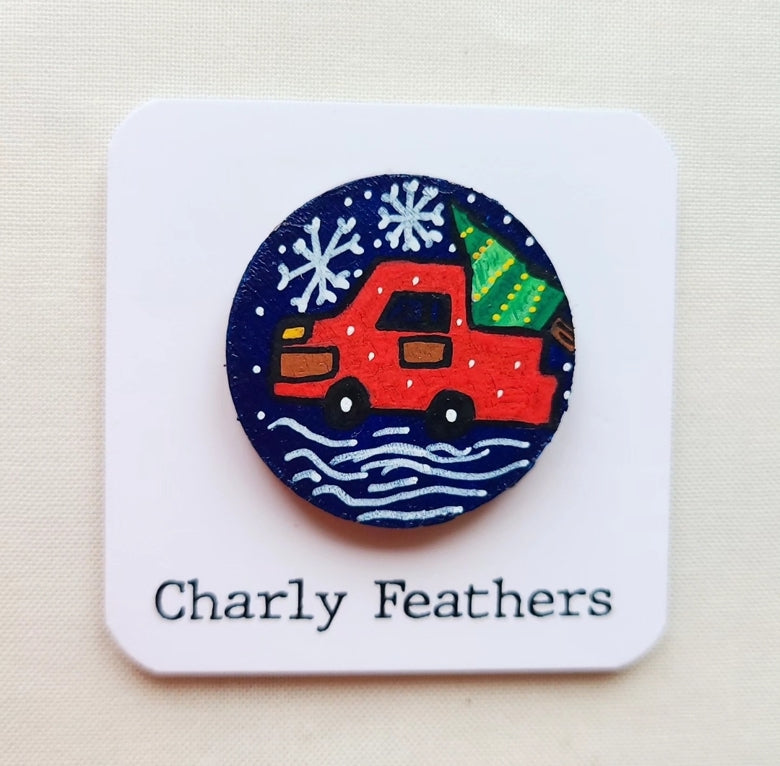 needle minder with a red car and Christmas tree design on a blue background, branded 'Charly Feathers'.