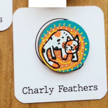 illustration of calico cat on an orange rug on turquoise needle minder