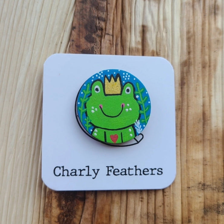 frog prince illustration on wooden needle minder with charly feathers branding
