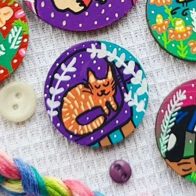 illustration of ginger cat on purple sofa on needle minder