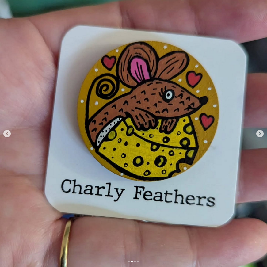 needle minder with a mouse with cheese illustration and 'Charly Feathers' text held in a hand.