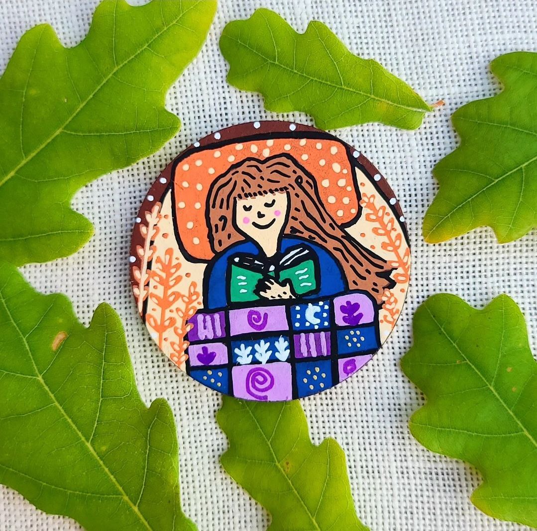 hand painted illustration of girl reading in bed on large needle minder