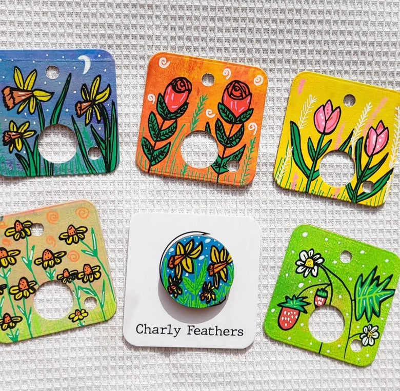 Set of colorful cardboard floss drops with floral and nature designs on a textured surface.