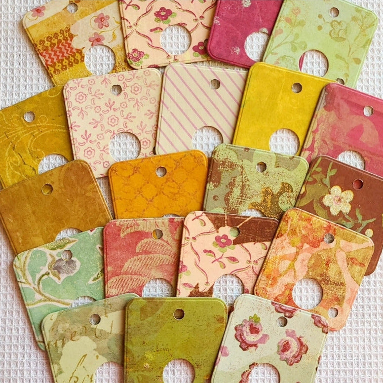 Collection of colorful floral and patterned square tags on a textured white background
