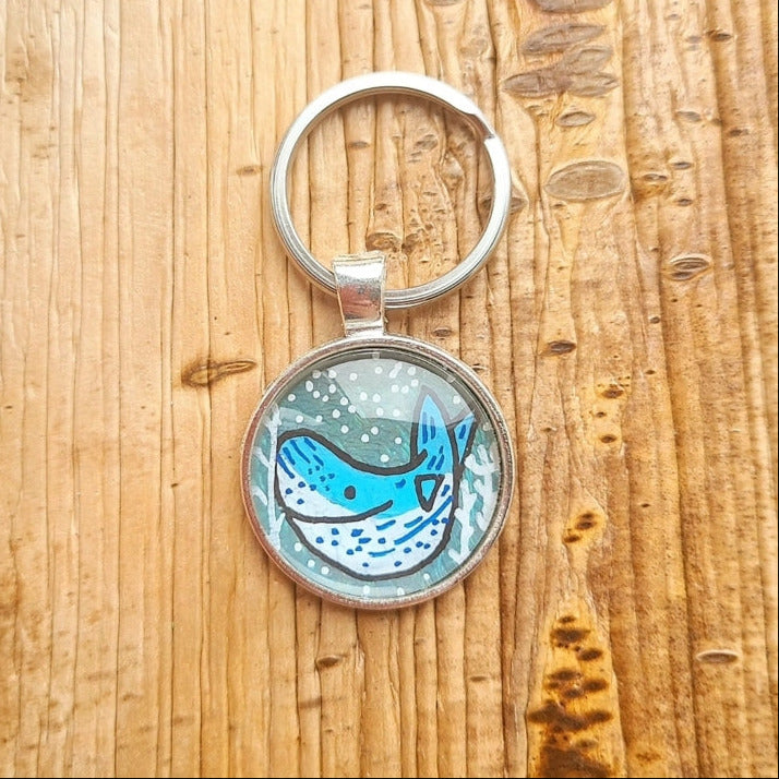 Keychain with blue whale design on a wooden surface
